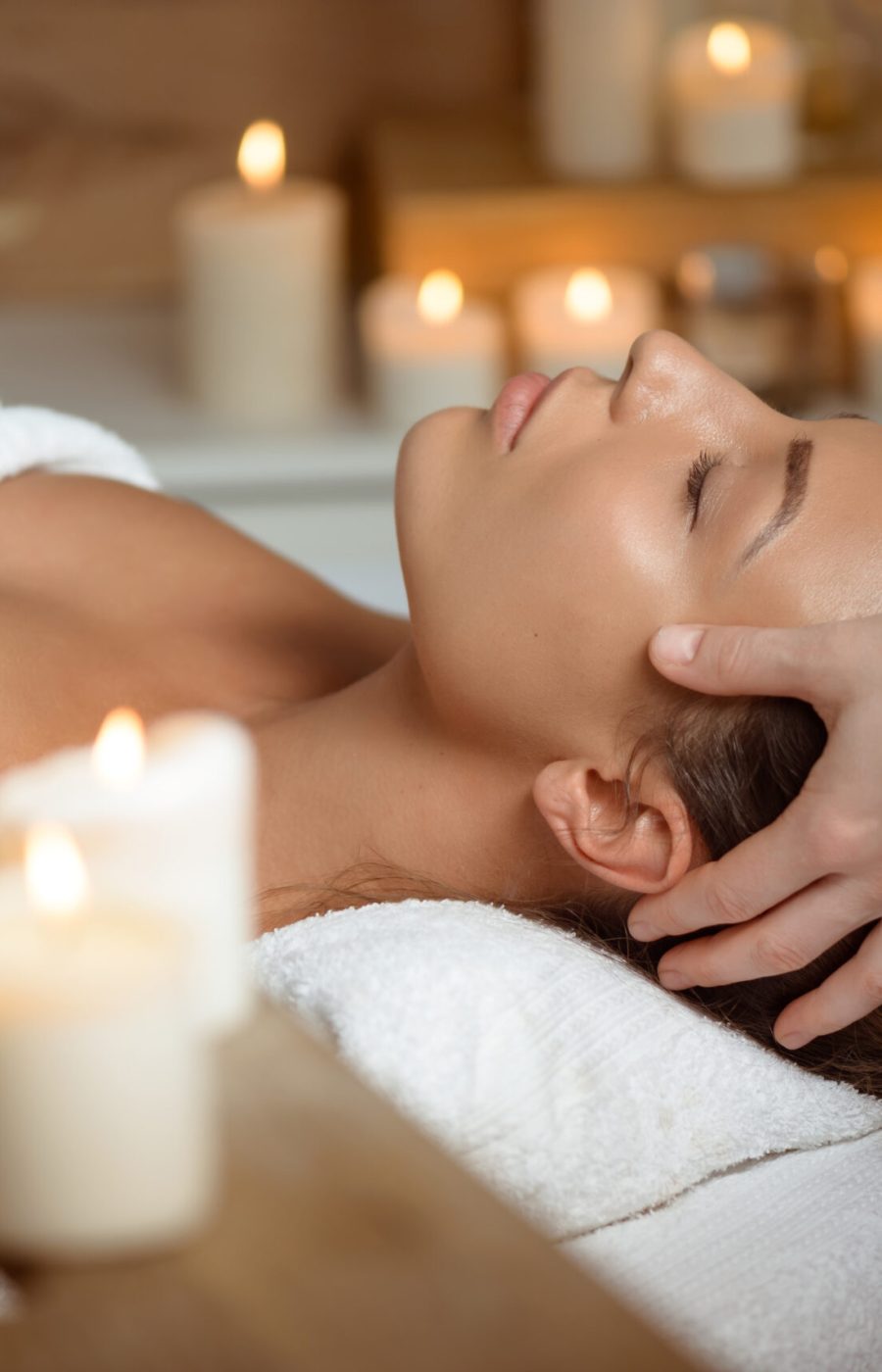 Young beautiful brunette girl having face massage relaxing in spa salon. Eyes closed. Copy space.